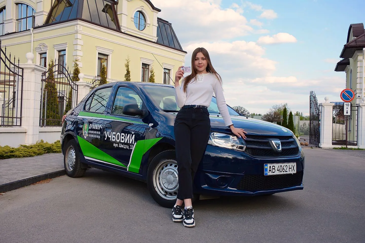 Молода жінка з посвідченням біля навчального автомобіля Dacia